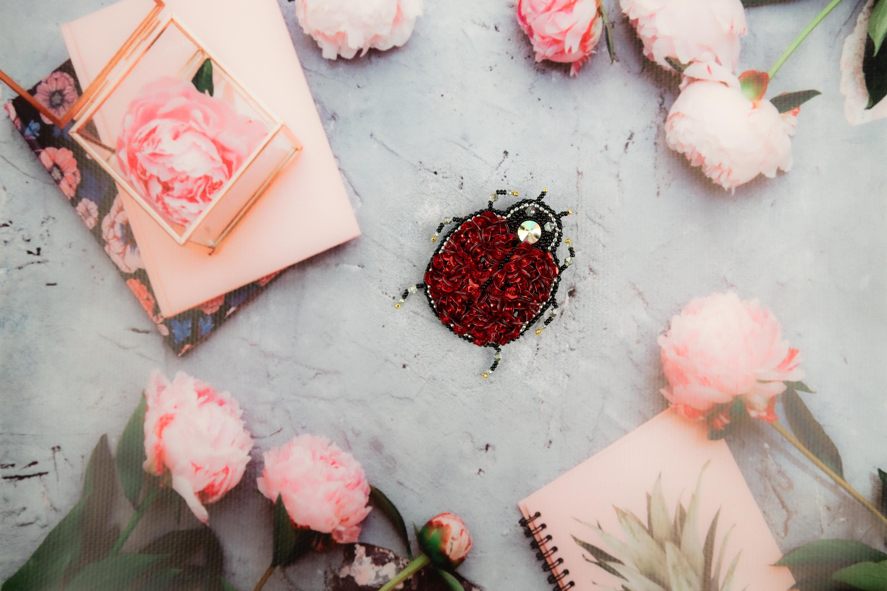 a heart shaped brooch sitting on top of a table next to flowers
